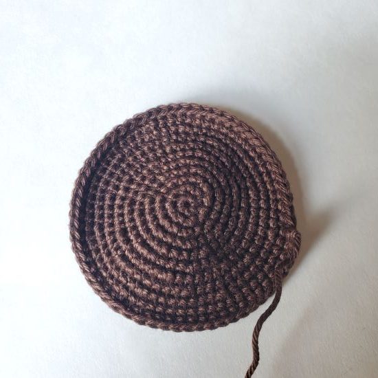 A brown crochet circle that is the front or back of the paleta