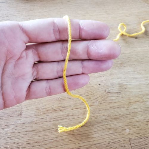 Yarn draped over a hand, step 1 of making a magic ring