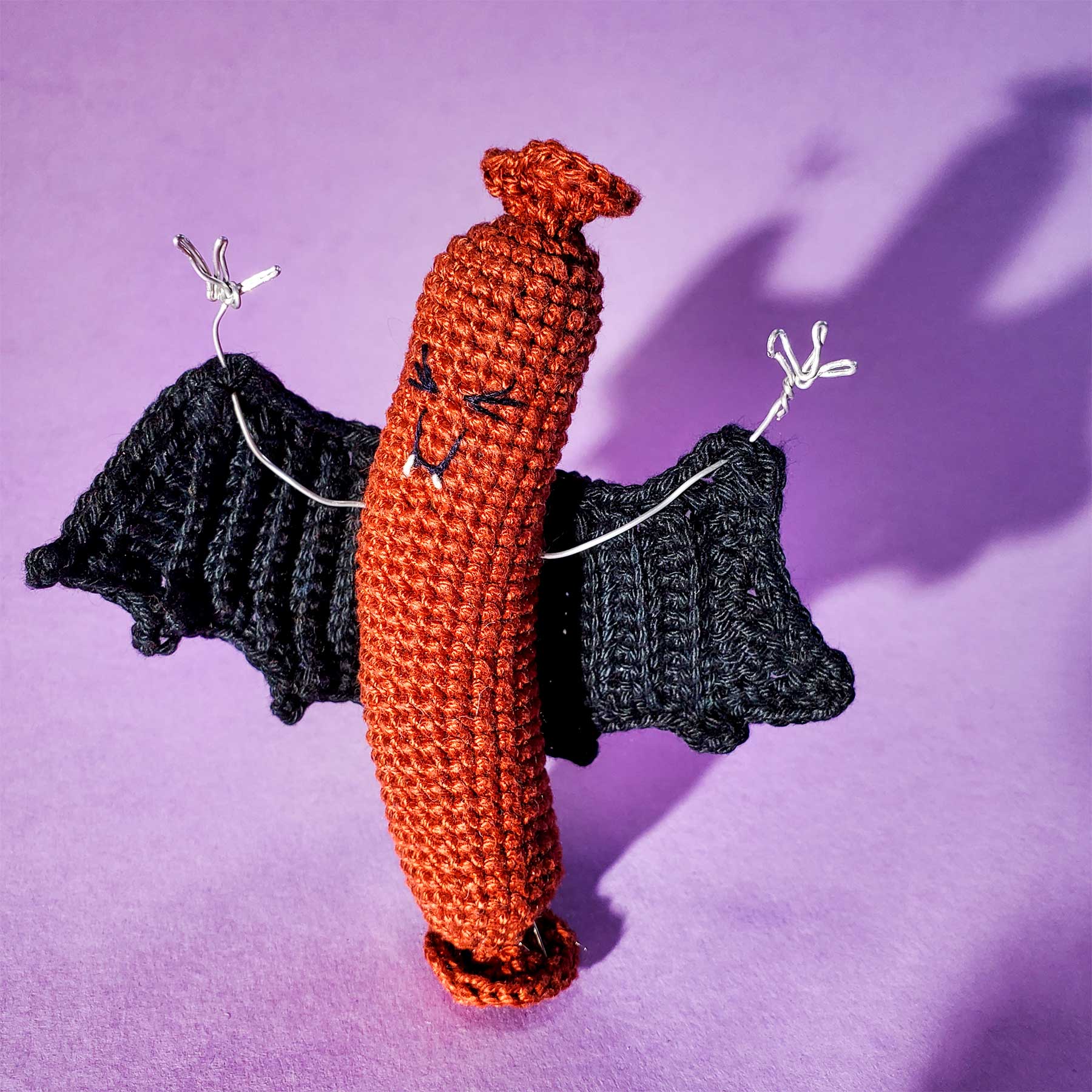 A crochet hotdog wearing a vampire cape