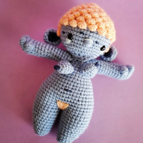 a crocheted woman with light pink hair