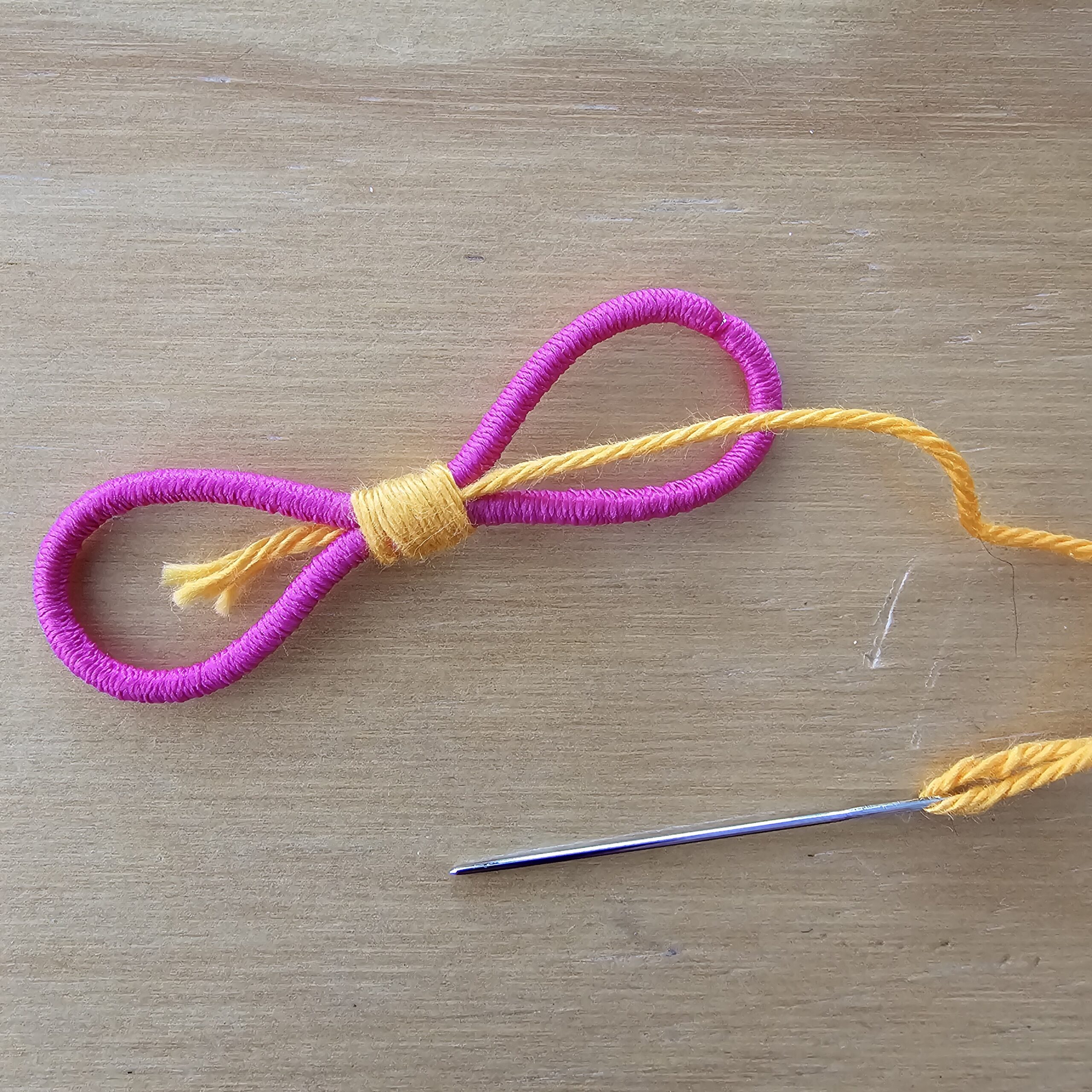 Wrap the yarn around the  starting tail then thread it through the center of the hairband.